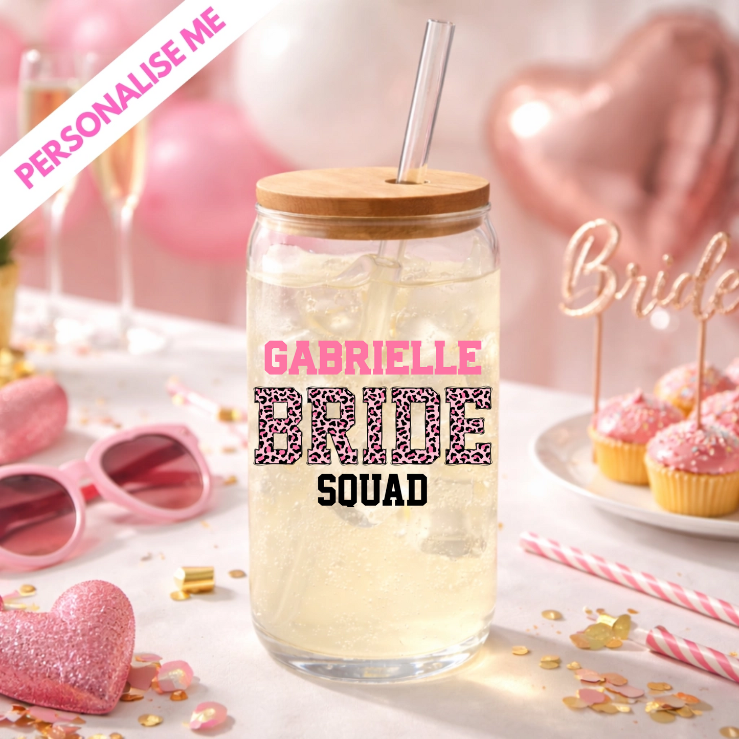 Clear glass jar with wooden lid and straw, personalized with 'Gabrielle Bride Squad' text, on a festive background with pink balloons and confetti.