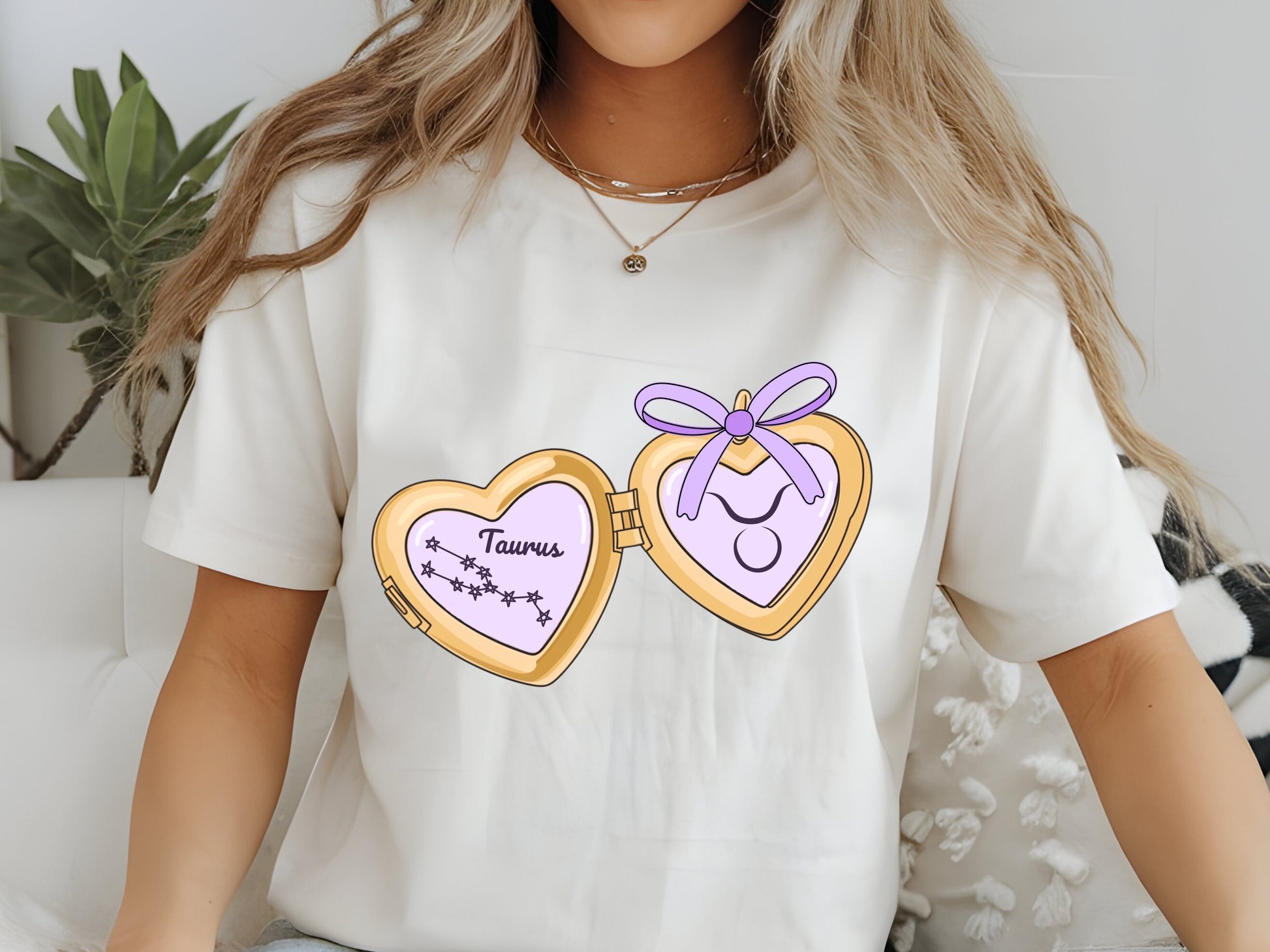 a cute trending and popular PNG digital download design of a gold love heart locket featuring a zodiac star sign and constellation symbol, finished with a purple lilac bow.  Can be used to create physical stickers or use for sublimation on clothing such as t shirts, jumpers and canvas bags