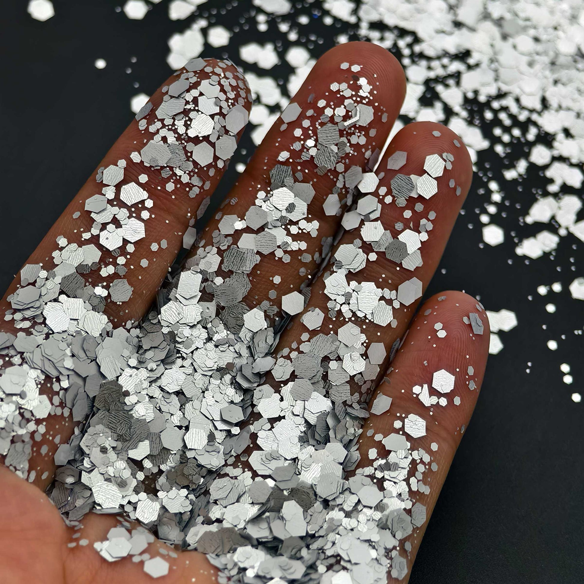 Hand holding silver glitter with a black background