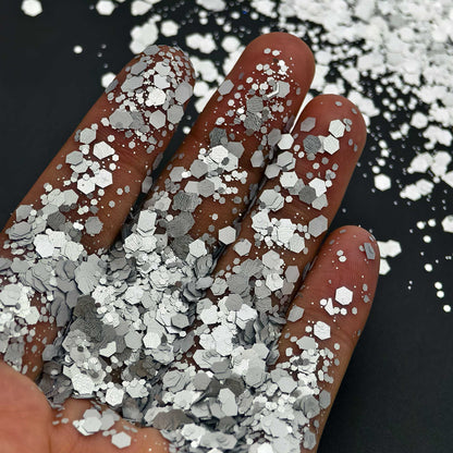 Hand holding silver glitter with a black background