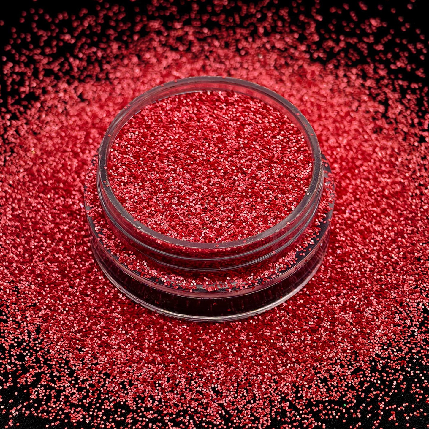 Red glitter in a small glass container on a black background