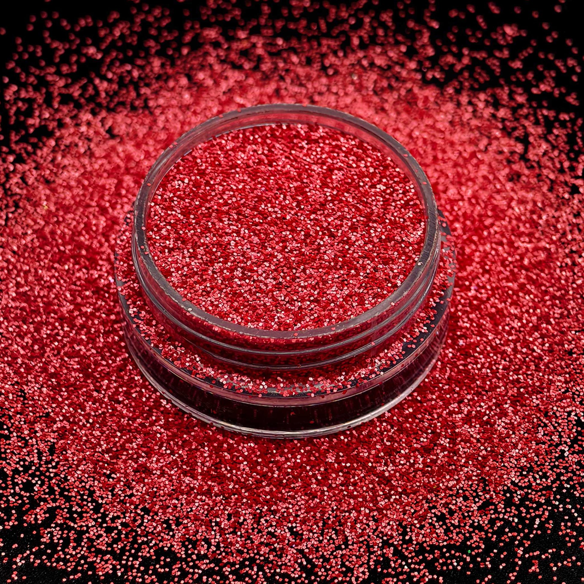 Red glitter in a small glass container on a black background