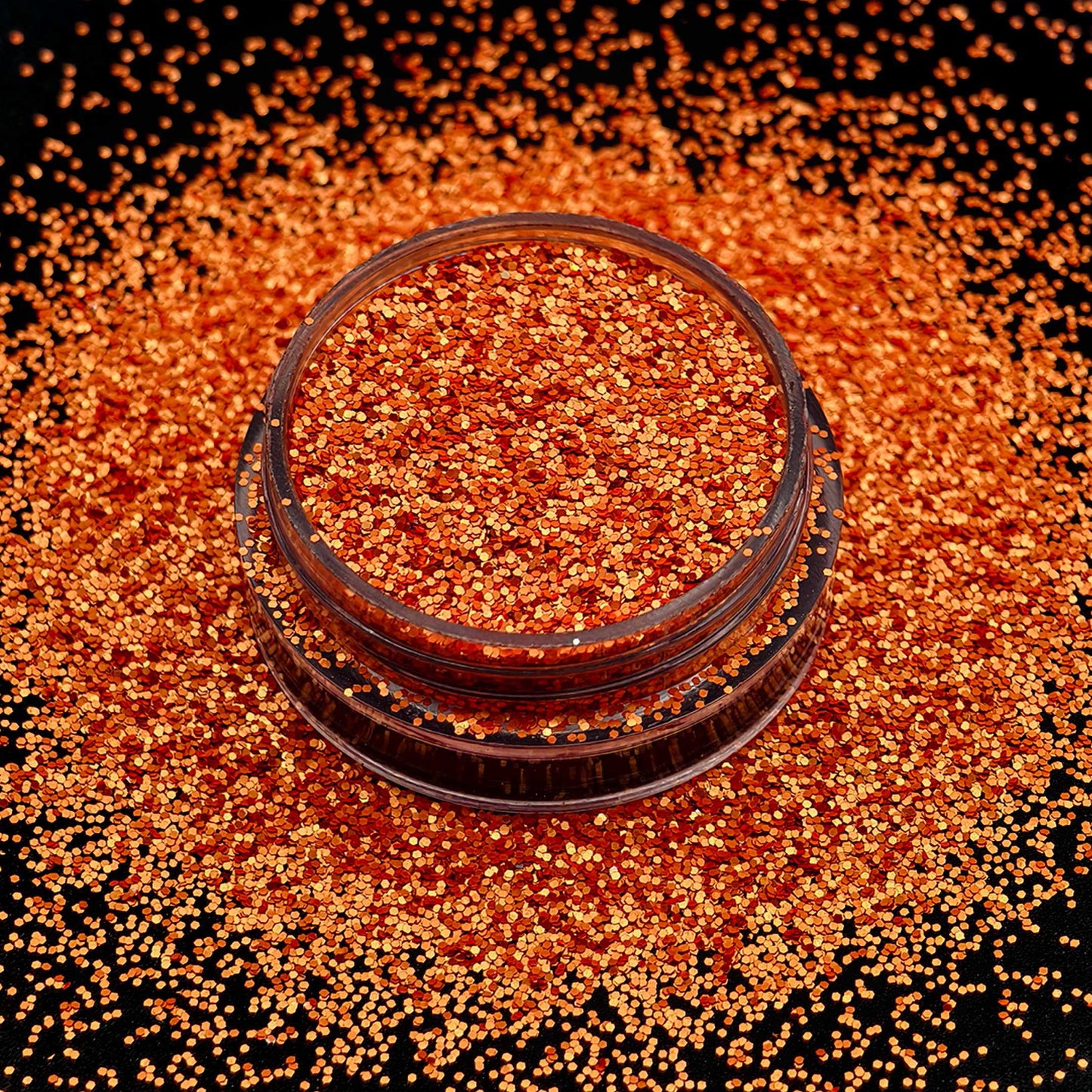Jar of orange glitter on a black background