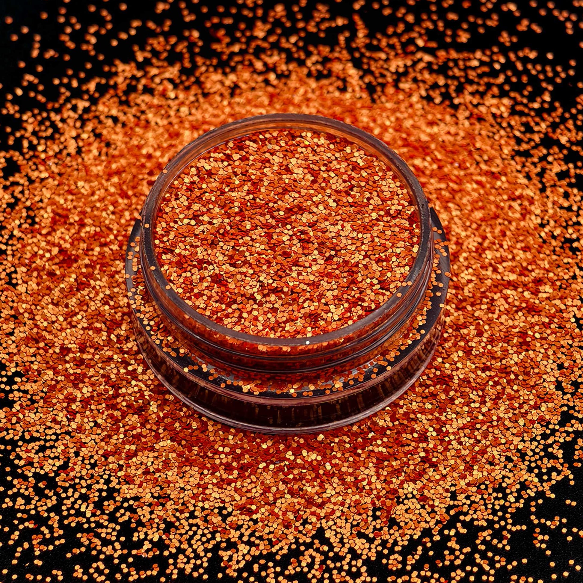 Jar of orange glitter on a black background