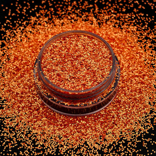 Jar of orange glitter on a black background