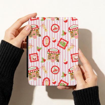 A person holds a tablet case with a pink and white striped pattern featuring cute cafe illustrations, set against a plain off-white background.
