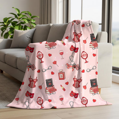 Pink smut romance seamless pattern displayed on a blanket with spicy book stacks, red lingerie, heart motifs and reading accessories.