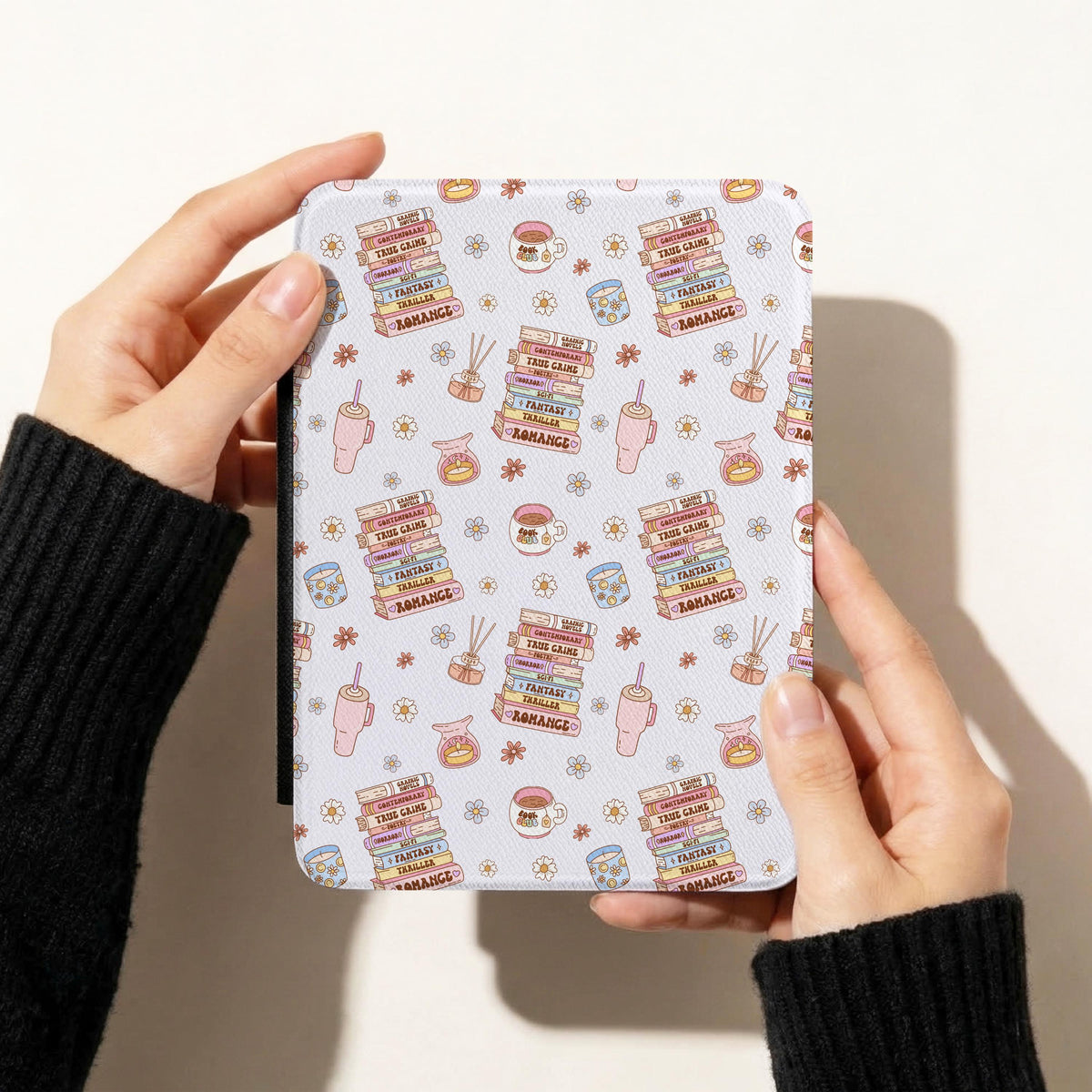 Pastel bookish reading club seamless pattern displayed on a Kindle cover featuring colourful book stacks, floral details, coffee mugs and candles.