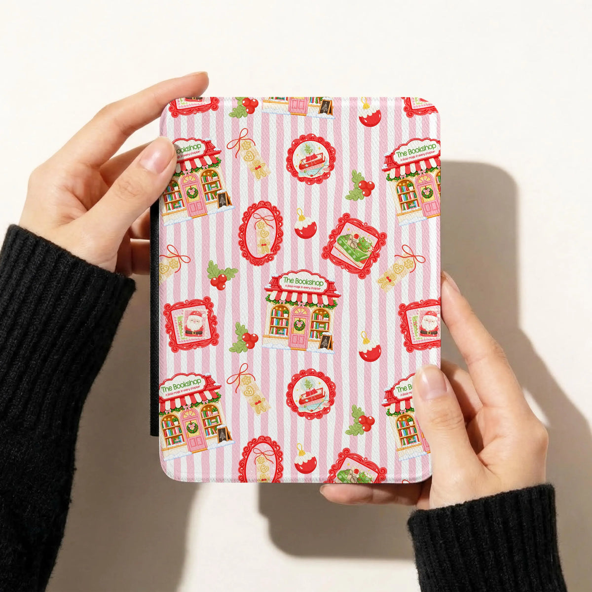 Pink Christmas bookshop seamless pattern displayed on a Kindle cover featuring festive bookstores, red vintage decorations, snowflakes and holly berries.