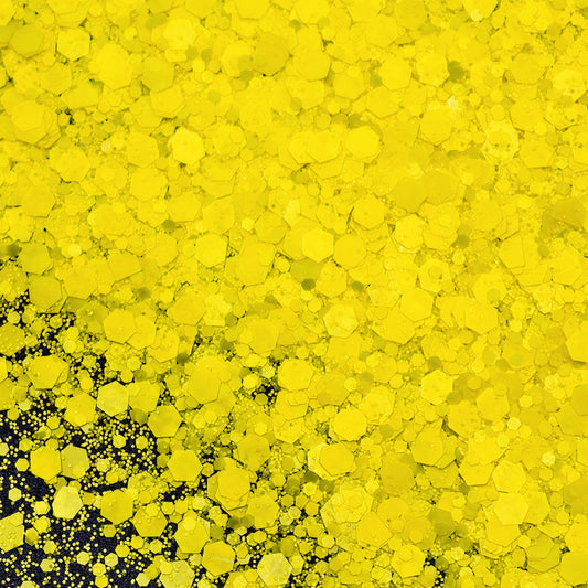 Close-up of yellow hexagonal glitter on a black background