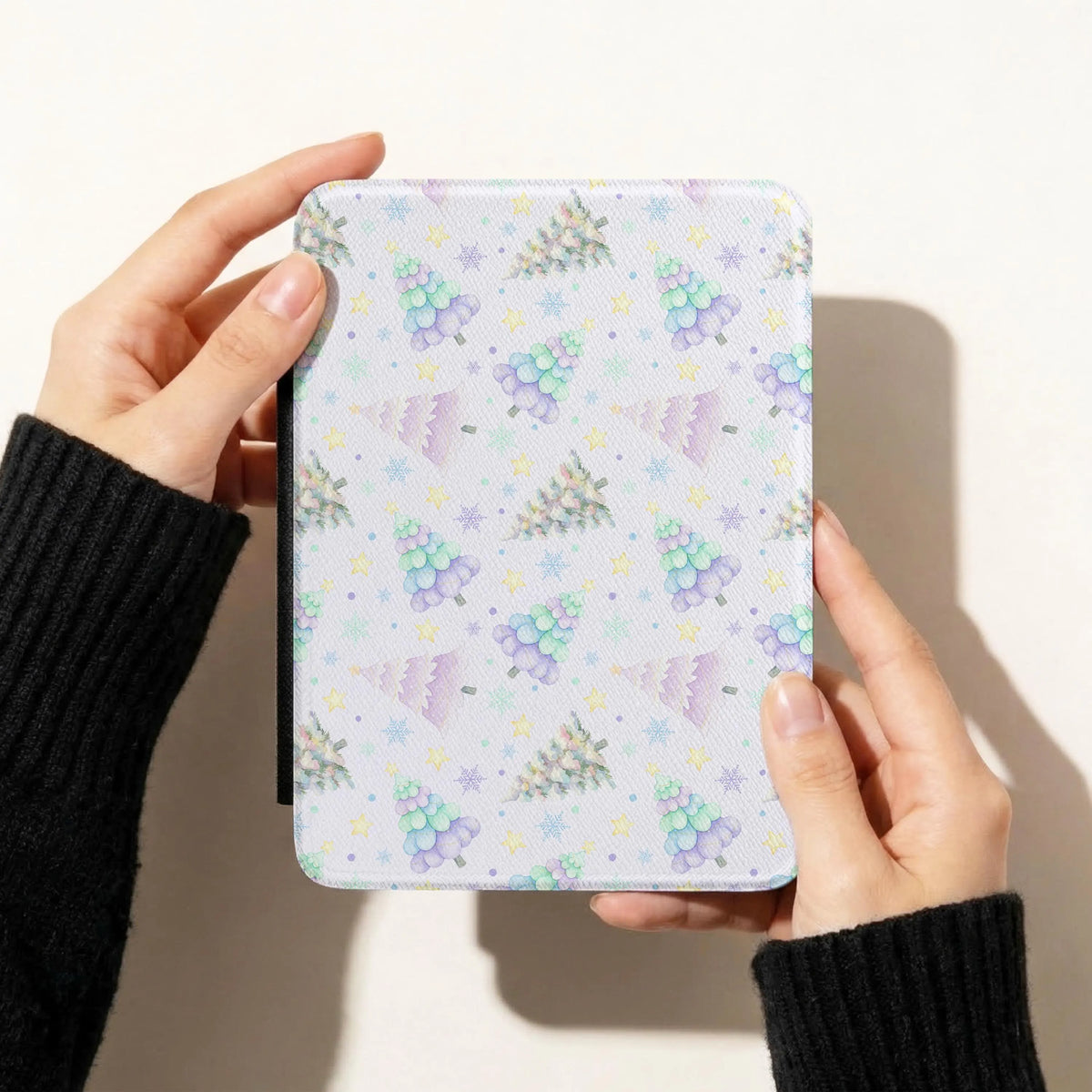 Pastel Christmas trees seamless pattern on a Kindle case featuring lavender, mint and blue watercolour trees, snowflakes and yellow stars.