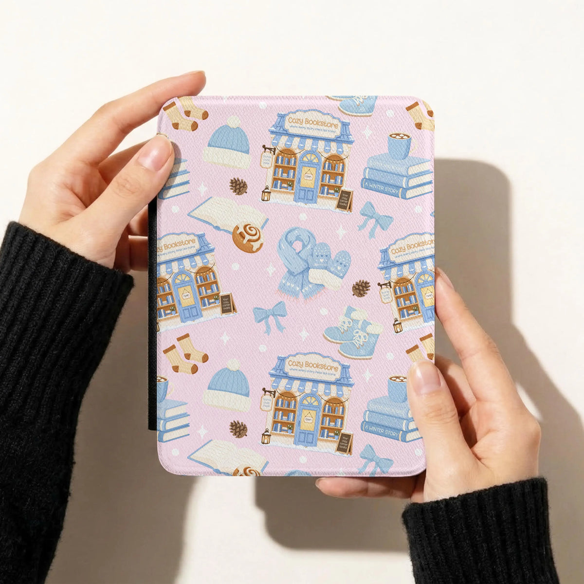 Pink winter reading seamless pattern displayed on an e-reader case with cozy bookstores, books, blue bows and winter accessories.