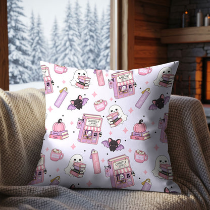 Ghostly Books Halloween seamless pattern displayed on a decorative cushion with pastel pink bookshops, cute ghosts, bats and spooky reading accessories.