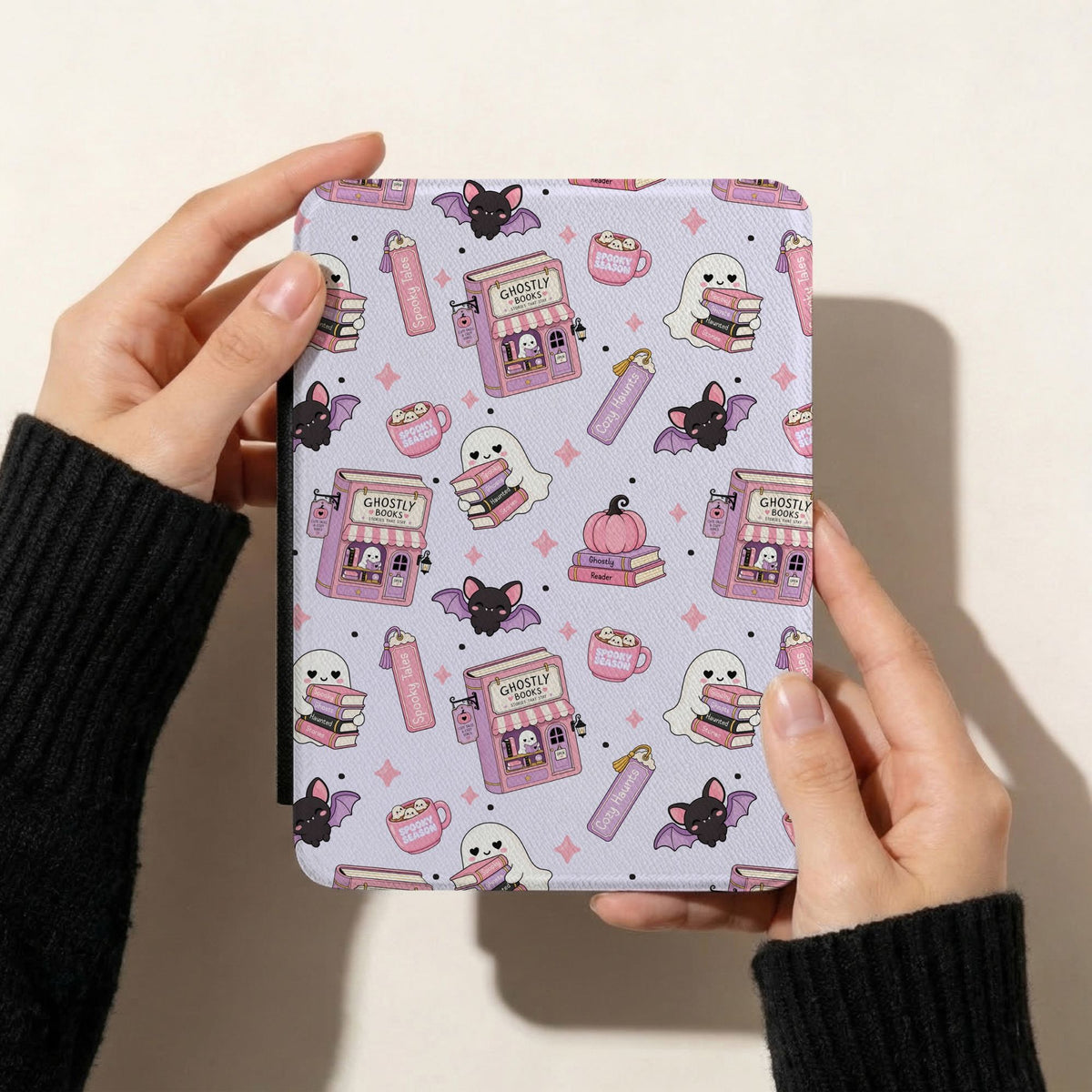 Pastel Halloween bookish seamless pattern displayed on a Kindle cover with cute reading ghosts, pink haunted bookshops, black bats and pumpkins.